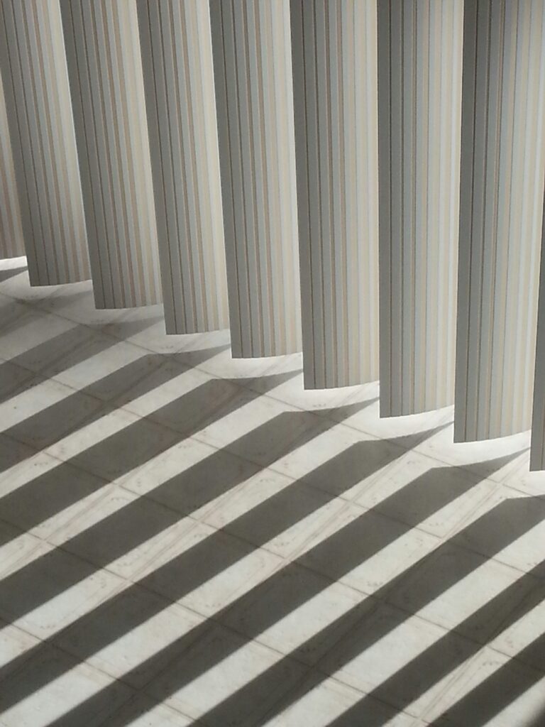 Abstract vertical blind shadows on linoleum floor